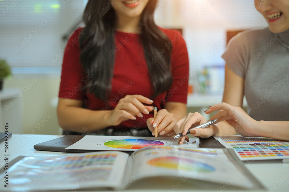 Fototapeta premium Close up of two young women hands discussing color palette and graphic design samples, creative teamwork and planning process in office.