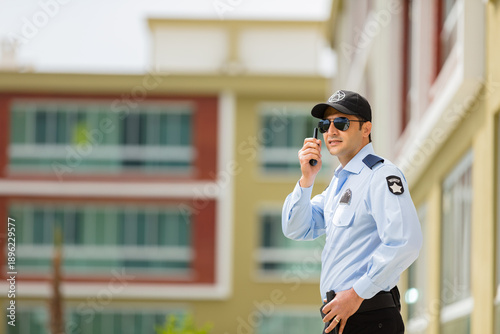 Bild auf Leinwand Private security guard wearing black cap and sunglasses, monitoring area with communication device