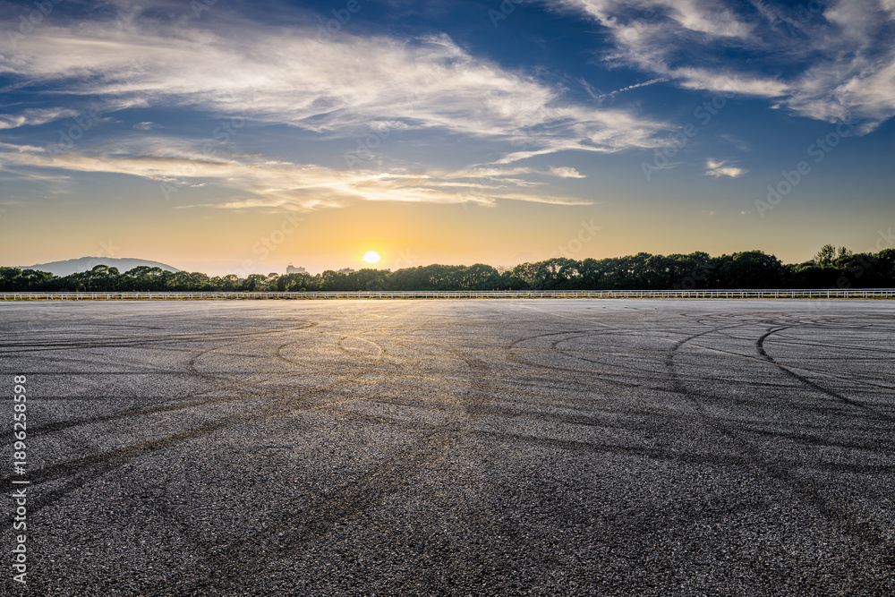 Obraz premium An empty asphalt road and tire tracks under a beautiful sunset sky