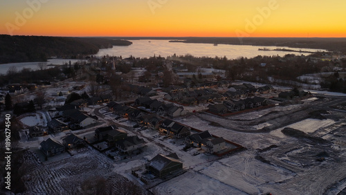 Sunrise showing town in shadow orange glow before the sun and a cold winter setting with frozen lake