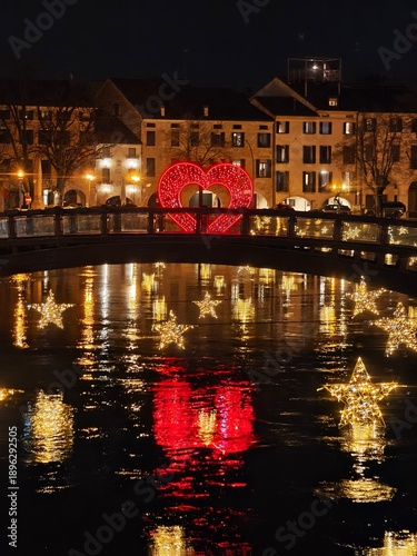 Romantic night in Treviso, Italy: Bridge over Sile River with illuminated red heart structure and glowing floating stars reflecting in dark water. Valentine's Day decorations in historic center
