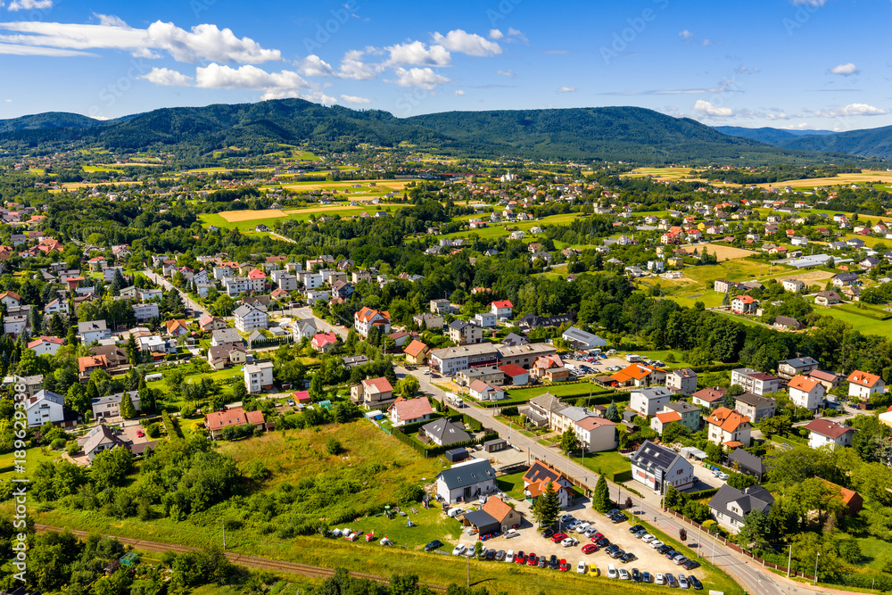 Fototapeta premium Aerial panoramic view of disperse housing of residential district of Andrychow city with Beskidy Mountains in background in Lesser Poland