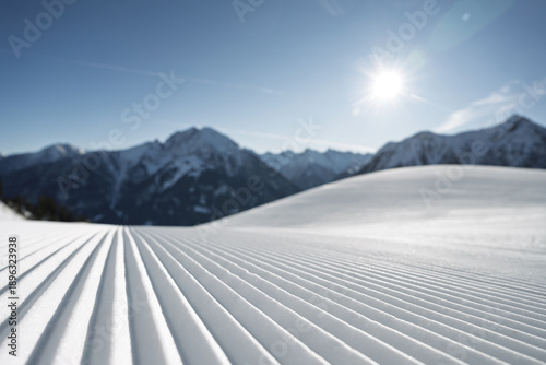 Canvas-taulu Corduroy snow texture on a freshly groomed ski slope with blue sky and distant blue alpine mountains in the background, captured during perfect Kaiserwetter winter conditions