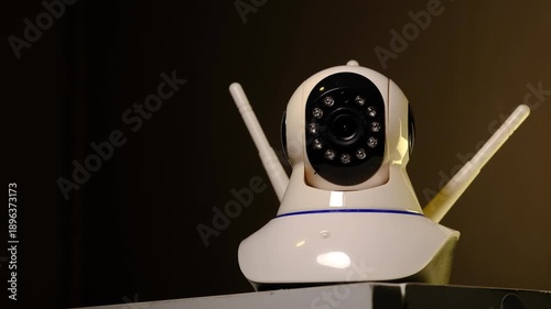 Smart CCTV Security Camera Home Surveillance Technology, Close up of a white security CCTV camera operating in a dark indoor environment.