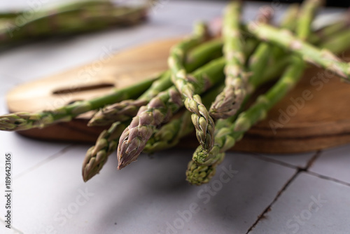 Fresh asparagus spears photographed at a slight angle with selective focus. Natural food ingredients captured in a rustic, minimal style, suitable for healthy cooking and organic food themes.