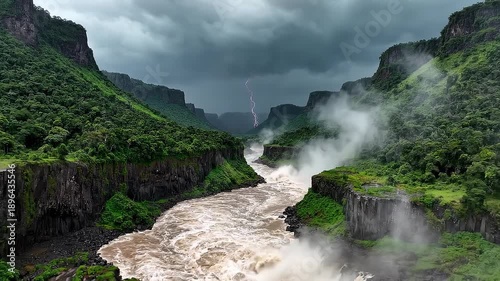 Wallpaper Mural Majestic Waterfall Cascading Through Lush Green Cliffs with Dramatic Stormy Sky and Lightning Torontodigital.ca