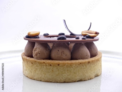 Fotografi Chocolate tartlet (shortcrust pastry, caramel, chocolate tuile, peanuts)