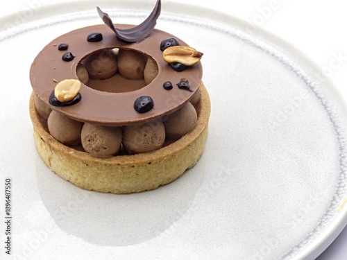 Foto Chocolate tartlet (shortcrust pastry, caramel, chocolate tuile, peanuts)