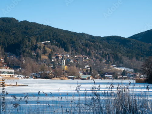 Silent Snowy Settlement Nestled Among Frosted Hills And Distant Majestic Mountains Under Clear Sky