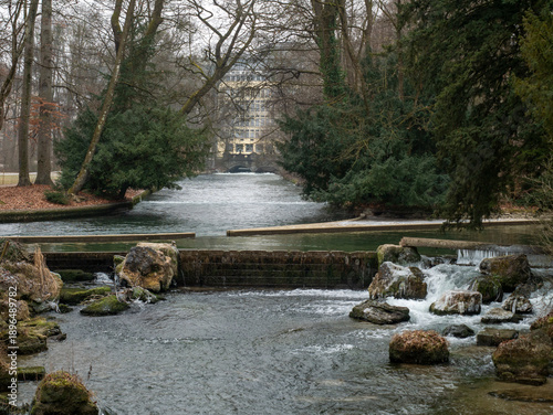 Serene Scene With Waterfall And Trees. Peaceful Winter Park With Flowing Water And Bare Trees