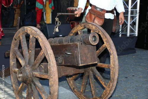 Medieval wooden cannon with iron barrel displayed during a historical reenactment festival. Authentic antique artillery on wheels, representing medieval warfare, military history.