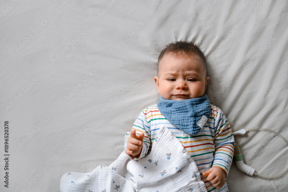 Fototapeta premium A baby is laying on a bed with a blue bandana around its neck.