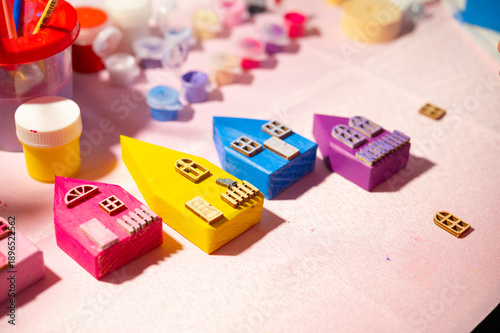 Wooden toy colorful houses children's background, selective focus. Painting wooden houses and gluing windows and doors. A children's hobby and activity.