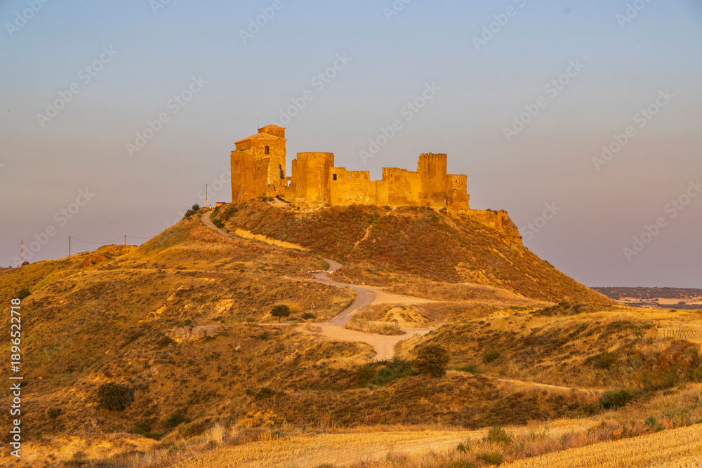 Obraz premium Castillo de Montearagon ruins on a golden hill at sunset