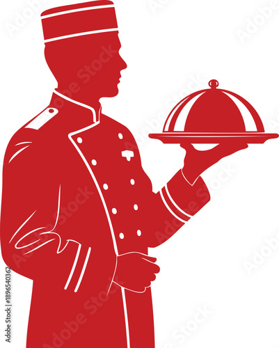 A chef in uniform holding a serving dish with a lid, standing in a restaurant kitchen, viewed from the side.