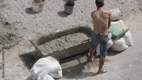 Worker Mixes Concrete Using a Shovel
