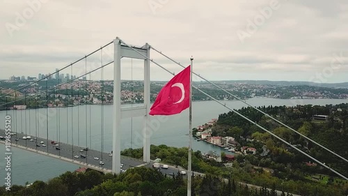 The Turkish flag waving in front of the Bosphorus Bridge. The first bridge built between Asia and Europe. Aerial view of the 15 July Martyrs Bridge. 