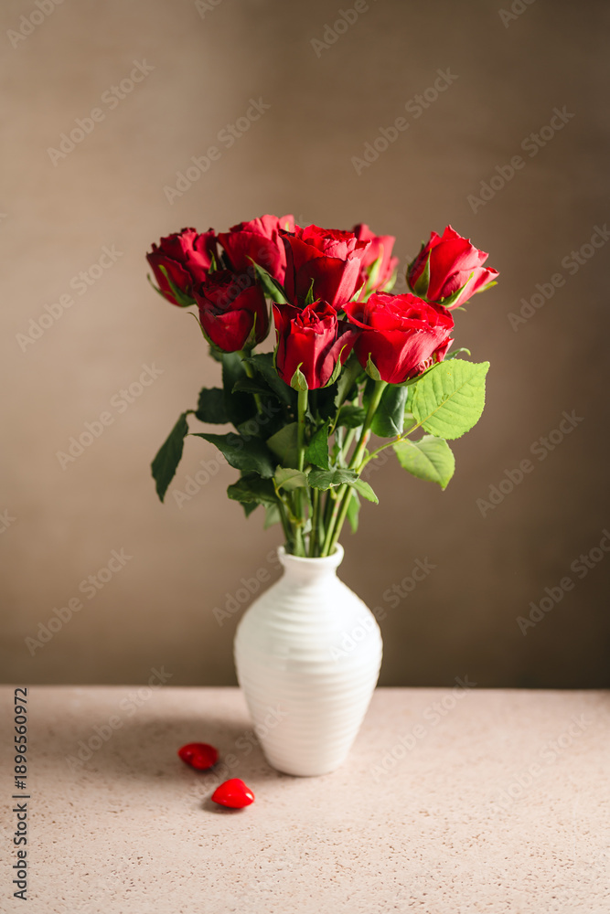 Obraz premium Valentine's Day festive background. Red roses flowers in a vase and hearts on neutral background. Festive greeting card, flat lay