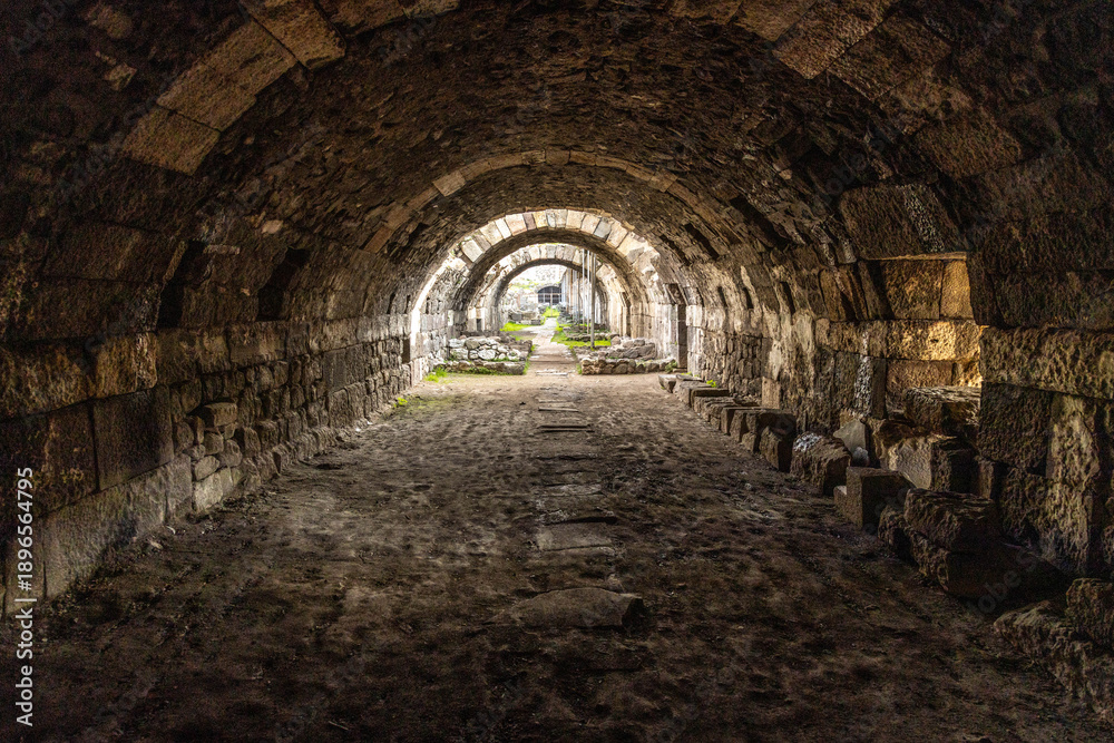 Fototapeta premium Ancient stone arches of the Agora of Smyrna in Izmir, Turkey. Perspective view inside the ruins of a Roman basement with historic masonry and pillars during a bright day