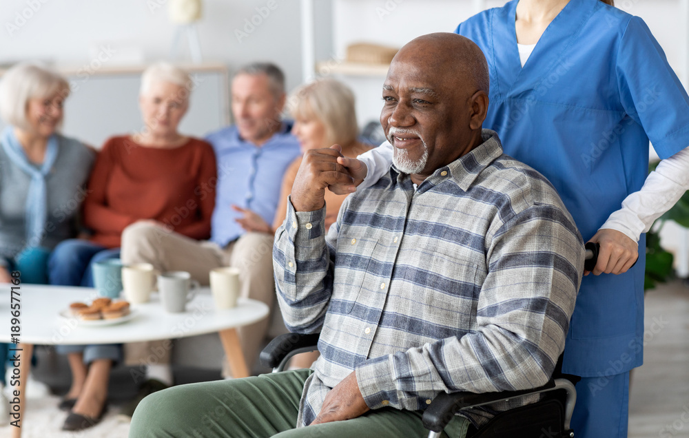 © Prostock-studio - Disabled african american senior man in wheelchair holding nurse hand, looking at copy space and smiling, thanking for support, life in nursing home for elderly people concept