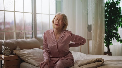 Wallpaper Mural Sad mature woman suffering back pain while sitting on bed, disc protrusion Torontodigital.ca