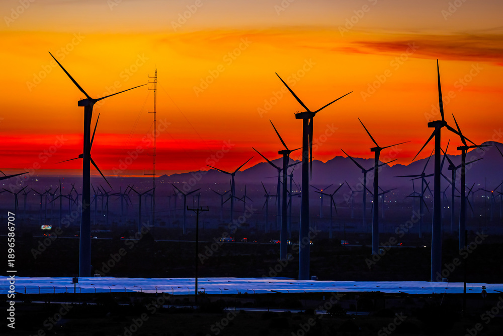 Fototapeta premium Scenic crimson panoramic sunset in California with multiple wind energy turbines silhouettes