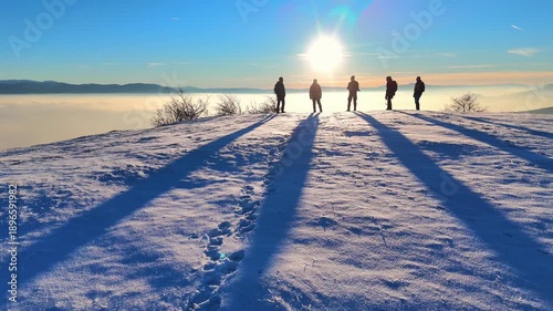 Silhouette of a hikers on top of hill. Winter outdoor sports activity. 