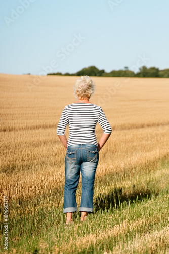 Rear outdoor view of woman looking out over farmland.