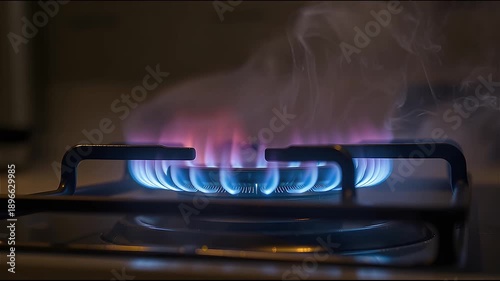 Close up of gas stove burner with blue flames igniting and producing smoke, showing energy consumption concept