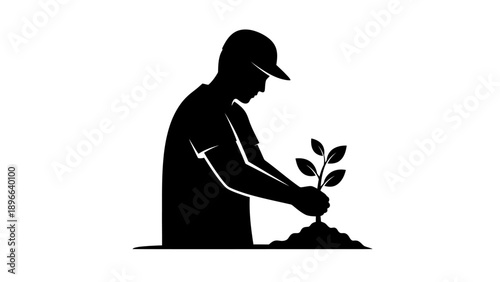 Silhouette of a person planting a tree seedling in soil.
