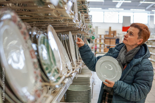Middle aged woman choosing home goods in large supermarket, everyday consumer decision and household shopping
