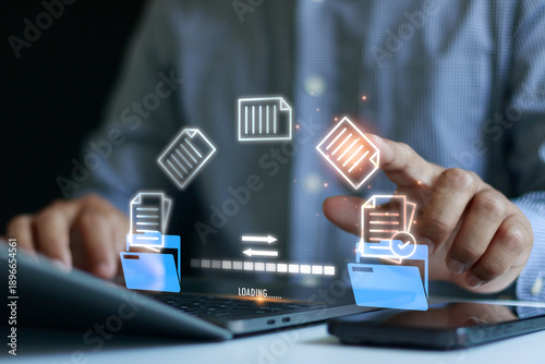 Businessman using laptop to manage digital document with file transfer interface, data exchange, cloud storage, workflow automation, document management system concept for modern business technology.