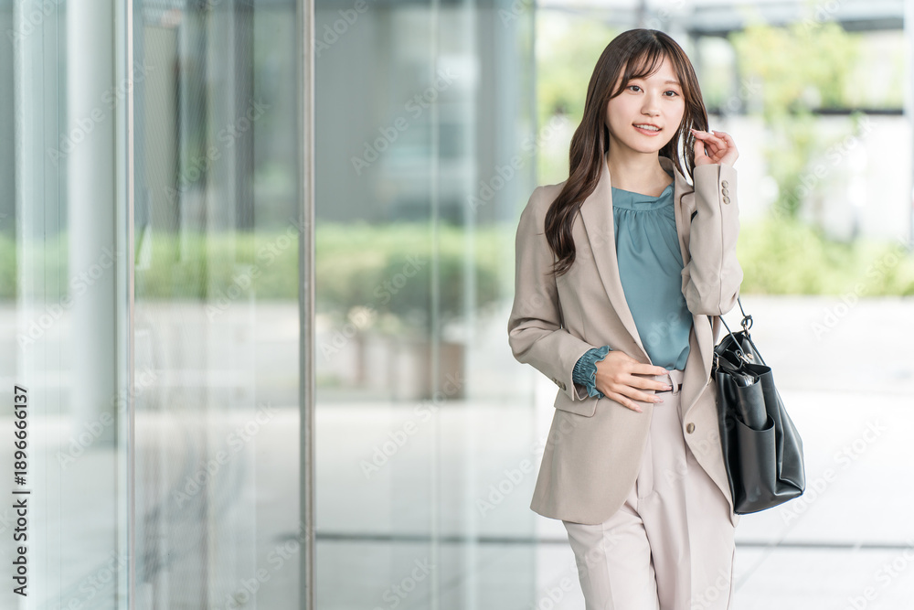 Fototapeta premium Young Asian businesswoman walking in an urban office district