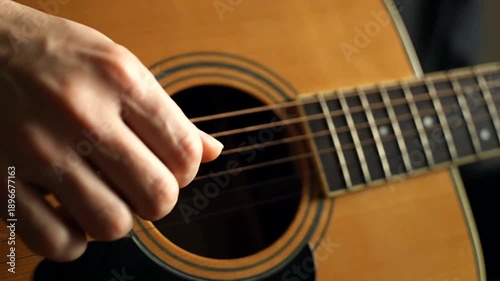 Close up of a person playing an acoustic guitar strumming the strings.