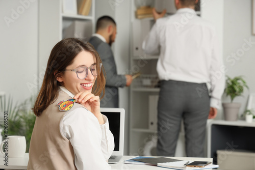 Billede på lærred Young businesswoman with paper fish on her back in office