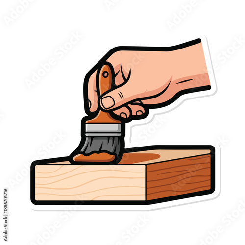 A hand holding a paintbrush painting on a wooden block