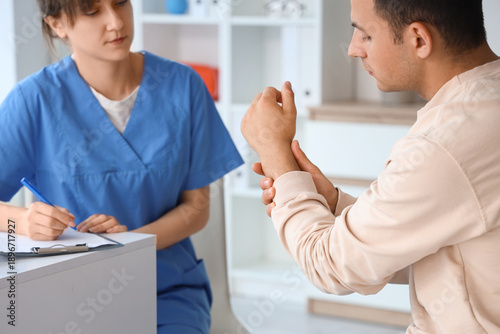 Young man with pain in his wrist visiting doctor at hospital