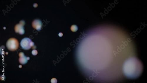 Abstract background features a dynamic scattering of colorful bokeh light orbs against a deep black void symbolizing mystical energy or digital data flow in a dark environment.
