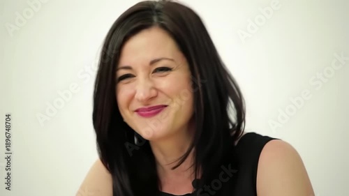 Smiling brunette in a black top against a plain white backdrop