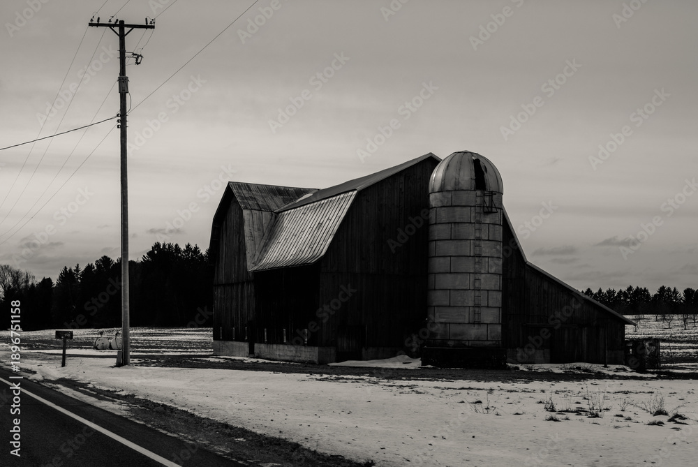 Obraz premium A historic barn by a country road during the winter in Northern Michigan