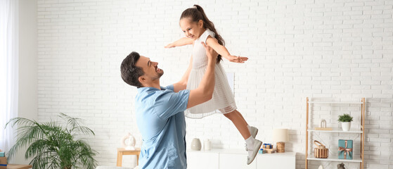 Father taking daughter in his arms in living room. Father's Day celebration