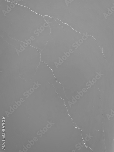 A high-resolution top-down view of a smooth, dark grey stone surface accented by delicate, lightning-like white veins, perfect for luxury interior backdrops.