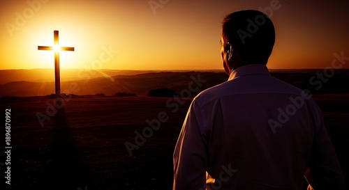 Man looking at cross at sunset. Spiritual pilgrimage and religious contemplation in beautiful dramatic light. Faith concept.