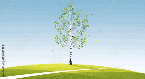 A lone birch tree standing tall on a vibrant green hill under a clear blue sky