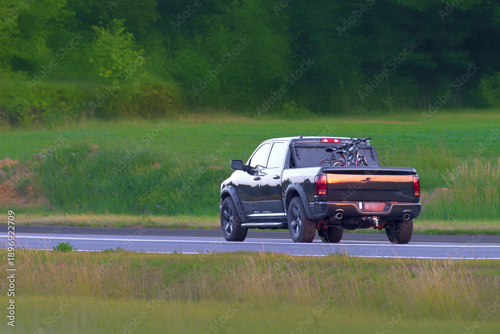 Fototapeta premium Automobile driving through countryside with mountain view