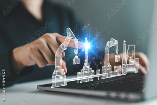 Businessperson with digital smart factory interface on laptop. Concept of robotic arms, automated conveyor systems, Industry 4.0, digital manufacturing, automation and intelligent production lines.