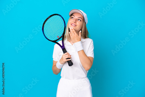 Bild auf Leinwand Young tennis player Romanian woman isolated on blue background looking up while