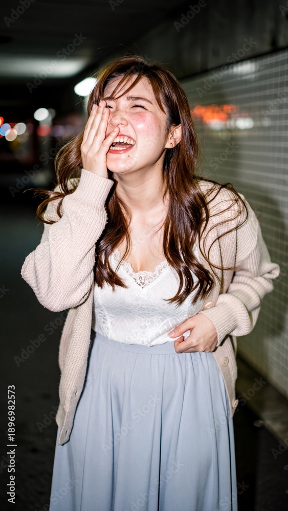 Fototapeta premium Joyful Japanese woman laughing heartily in a city tunnel at night