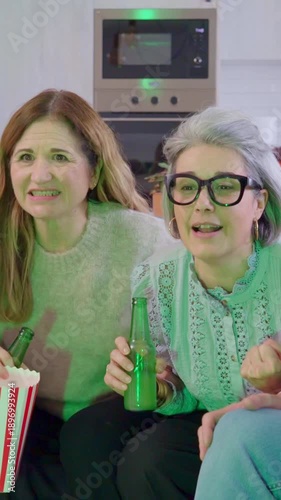 Mature women friends watching a thrilling sports game on tv