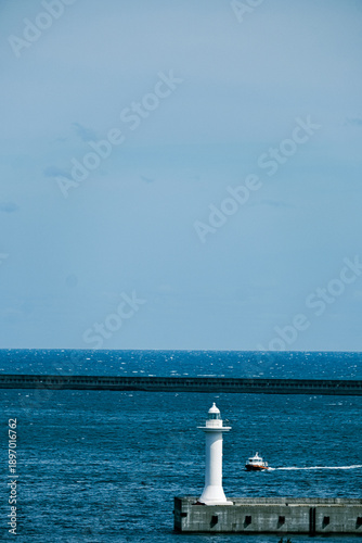 White lighthouse on breakwater with blue ocean and copy space.